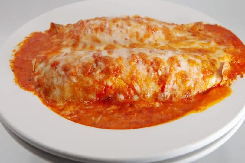 Two cheese enchiladas covered in red sauce and melted cheese on a white plate.